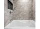 Relax in this tub featuring neutral tiled walls and chrome fixtures at 127 Pebblebrook Way, Temple, GA 30179