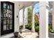 Inviting front porch featuring white columns, a black front door, and manicured landscaping at 1485 Mill Place Dr, Dacula, GA 30019