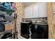 Functional laundry room with black washer and dryer, storage shelves, and floral wallpaper at 1485 Mill Place Dr, Dacula, GA 30019