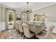 Elegant dining room features a statement chandelier, large window, neutral paint, and a large table with seating for eight at 284 Hook St, Alpharetta, GA 30009
