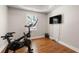 Bright exercise room with wood floors, stationary bike and a wall-mounted television at 160 Brookhollow Trce, Alpharetta, GA 30022