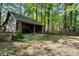 View of the rustic log cabin with a covered area, surrounded by lush trees and natural landscaping at 3401 Clay Rd, Austell, GA 30106