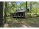 Charming log cabin with a covered front porch nestled among mature trees at 3401 Clay Rd, Austell, GA 30106
