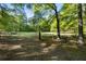 View of the expansive grassy lot surrounded by lush greenery, featuring a rustic wooden fence at 3401 Clay Rd, Austell, GA 30106