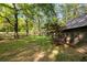 Side view of the cabin with a manicured lawn, surrounded by mature trees and natural landscaping at 3401 Clay Rd, Austell, GA 30106
