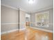 Neutral room with hardwood floors, wainscoting detail, window with blinds, and a view of the kitchen at 899 Fairwood Nw Way, Acworth, GA 30101