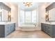 This bathroom has a soaking tub with a view between two sink vanities with mirrors at 4266 Paces Ferry Road Se, Atlanta, GA 30339