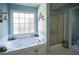 Bright bathroom featuring a soaking tub and a glass-enclosed shower at 7522 Greens Mill Dr, Loganville, GA 30052