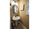 Charming powder room with pedestal sink, decorative mirror, and neutral color scheme at 7522 Greens Mill Dr, Loganville, GA 30052