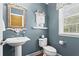 Stylish powder room with a pedestal sink, elegant mirror, and fresh blue paint at 203 Setters Rdg, Canton, GA 30115
