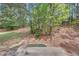 View of a natural wooded backyard, with scattered trees and a small concrete patio area, showcasing nature at 2640 Thunder Basin Way, Douglasville, GA 30135