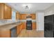 Well-lit kitchen featuring wood cabinets, black appliances, and wood flooring, ideal for everyday meals at 2640 Thunder Basin Way, Douglasville, GA 30135