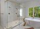 Beautiful bathroom with marble tile, a glass-enclosed shower with dual shower heads, and a freestanding tub by a window at 3290 Dunlop Ne Ct, Atlanta, GA 30319