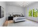 Bright bedroom featuring a large window, light wood flooring, neutral walls, and a modern chandelier at 3290 Dunlop Ne Ct, Atlanta, GA 30319
