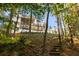 Back of a white three-story home with multiple decks, landscaping, and wooden steps at 3290 Dunlop Ne Ct, Atlanta, GA 30319