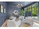 Sophisticated living room with dark blue walls, modern chandelier, and large windows overlooking lush greenery at 3290 Dunlop Ne Ct, Atlanta, GA 30319