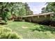 Wide view of backyard showing brick home, lush green lawn, and mature trees for privacy at 1280 Berkeley Rd, Avondale Estates, GA 30002