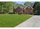 Charming two-story brick home with a lush green lawn, driveway, and green shutters at 2461 Peregrine Trl, Suwanee, GA 30024