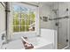 Soaking tub with tiled shower and scenic backyard views in a bright bathroom at 363 Ridge Run Dr, Hiram, GA 30141
