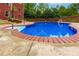 A kidney-shaped in-ground pool surrounded by a brick border and concrete deck at 51 Sagemont Ct, Acworth, GA 30101