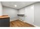 Well-lit laundry room with wood-look flooring, gray cabinets with wood countertop, and convenient wall shelf at 2663 Lowell Dr, Morrow, GA 30260