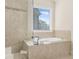 Bright bathroom showcasing a tiled shower, soaking tub, and a large window for natural light and outdoor views at 4343 Ainsley Mill Ln, Duluth, GA 30097