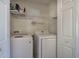 Bright laundry room with white washer and dryer and wire shelving, ready for chores at 5221 Huntcrest Sw Pl, Mableton, GA 30126