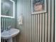 Stylish powder room with a pedestal sink, decorative mirror, and patterned wallpaper at 5221 Huntcrest Sw Pl, Mableton, GA 30126