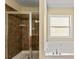Bathroom featuring a glass-enclosed shower, garden tub, and natural light at 7705 Bellmist Dr, Fairburn, GA 30213