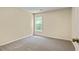 Neutral bedroom featuring a window, base trim, and neutral carpet at 7705 Bellmist Dr, Fairburn, GA 30213