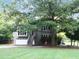 View of the home with large trees in the front yard, providing plenty of shade, and stairs leading to the front door at 821 Tramore Ct, Powder Springs, GA 30127