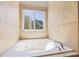 Corner bathtub offers a relaxing view of nature through a window at 345 Etheridge Rd, Auburn, GA 30011