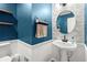 Stylish bathroom features a pedestal sink with decorative wallpaper and blue paint at 4213 Schooner Ne Ct, Roswell, GA 30075