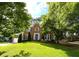 Charming two-story brick home with a well-manicured lawn, mature trees, and a welcoming blue front door at 4213 Schooner Ne Ct, Roswell, GA 30075