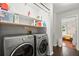 Bright laundry room featuring a modern washer and dryer, with shelving above for storage and a bedroom in the background at 4213 Schooner Ne Ct, Roswell, GA 30075
