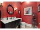 Elegant red bathroom featuring a black vanity with a marble countertop and a round mirror at 3562 Langley Oaks Se Ct, Marietta, GA 30067