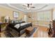Comfortable main bedroom with tray ceilings, ceiling fan, hardwood flooring, and a large window at 3562 Langley Oaks Se Ct, Marietta, GA 30067