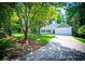 Serene home exterior featuring mature trees, a well-manicured lawn, a two-car garage, and a long driveway at 4694 E Glen Ridge E Cir, Winston, GA 30187