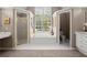 Bathroom featuring separate shower and soaking tub spaces, complemented by dual vanities and natural lighting at 2130 Federal Rd, Roswell, GA 30075