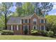Charming two-story brick home featuring a manicured lawn, lush landscaping, and dark green shutters at 2130 Federal Rd, Roswell, GA 30075