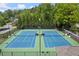 Aerial view of community tennis courts with fresh blue surface and mature trees around perimeter at 2130 Federal Rd, Roswell, GA 30075