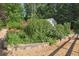 Lush landscaped yard featuring a stone retaining wall with various plants and a glimpse of the house in the background at 3704 Wilkins Cir, Powder Springs, GA 30127