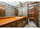 Bathroom with colorful wallpaper, cabinets with long vanity, and an open door revealing the commode and shower at 3865 Adams Rd, Cumming, GA 30041