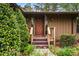 Inviting front entrance with a decorative wood door, well-manicured greenery, and rustic charm at 3865 Adams Rd, Cumming, GA 30041