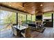 Beautiful covered patio with a stone fireplace, TV, ceiling fans, and an outdoor dining area, overlooking the lake at 7305 Breeze Bay Rd, Cumming, GA 30041
