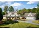 Beautiful exterior elevation of home with manicured lawn, circular driveway, and lush landscaping surrounding the property at 7305 Breeze Bay Rd, Cumming, GA 30041