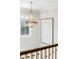 Bright hallway featuring a decorative chandelier, large artwork, and staircase with railing, adding sophistication at 7305 Breeze Bay Rd, Cumming, GA 30041