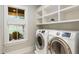 Convenient laundry room with modern washer and dryer, built-in shelving, and a window providing natural light at 7305 Breeze Bay Rd, Cumming, GA 30041