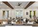 Spacious living room with hardwood floors, wood beams, and multiple seating areas with access to the outside at 7305 Breeze Bay Rd, Cumming, GA 30041
