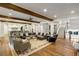 Open-concept living area with hardwood floors, wood beams, kitchen view, and staircase leading to the upper level at 7305 Breeze Bay Rd, Cumming, GA 30041